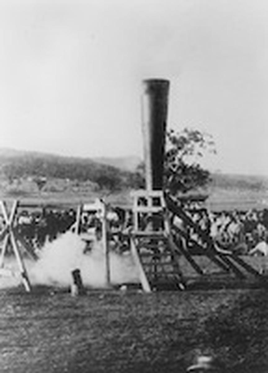 Crowd of people watching a small explosion of a Vortex Gun, Mount Morgan, 1902